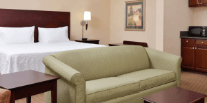 A Staunton, VA hotel with a large bed, a couch at the foot, and a small kitchenette behind it