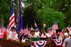 Large group of veterans in the Veterans Day Parade float holding American Flags