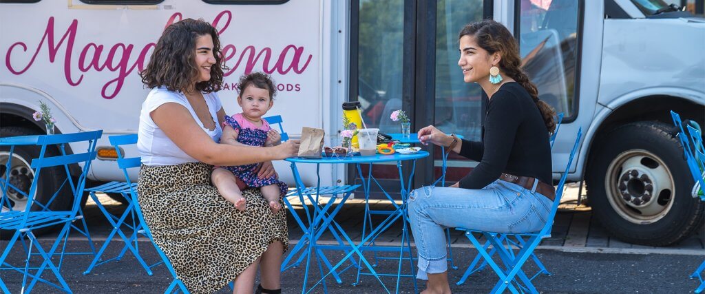 A family sitting near a food truck at a blue table while enjoying Hispanic Foods in Staunton