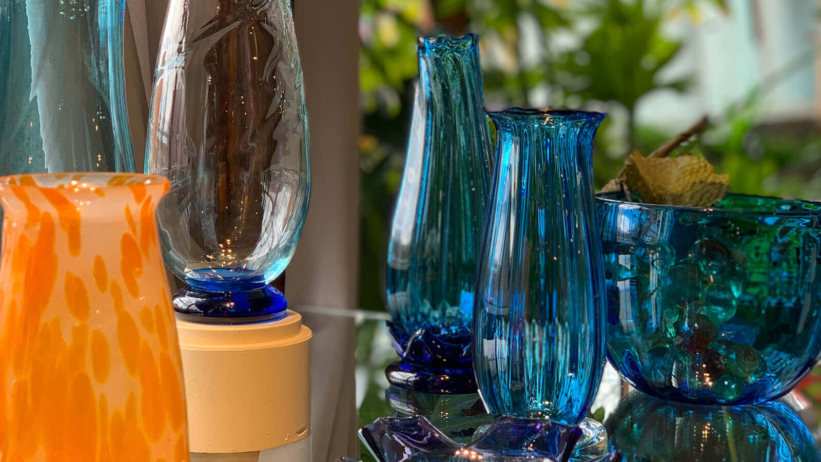 Beautiful handcrafted glass in blue tones sit on a table. 