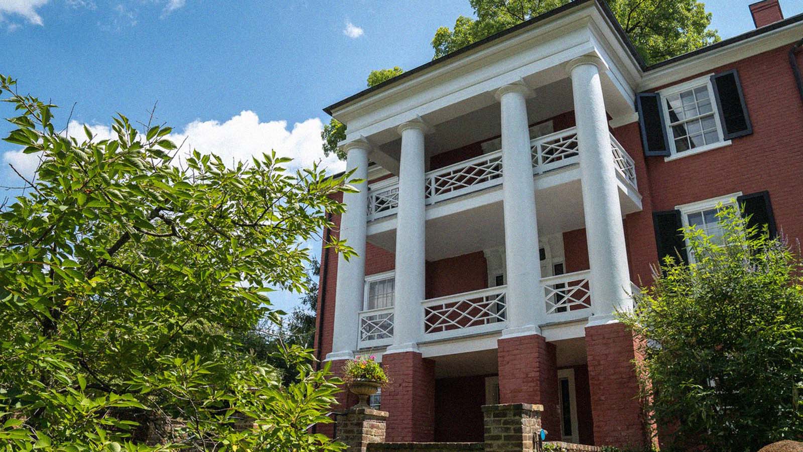A historic home made of red brick and white columns stands tall. 