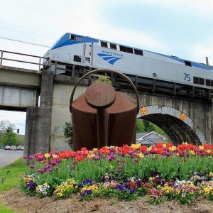 Amtrak train on overpass in Staunton with large watering can and flowers