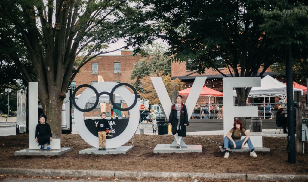 A group of people sitting on the ground, enjoying each other's company in front of a large love sign