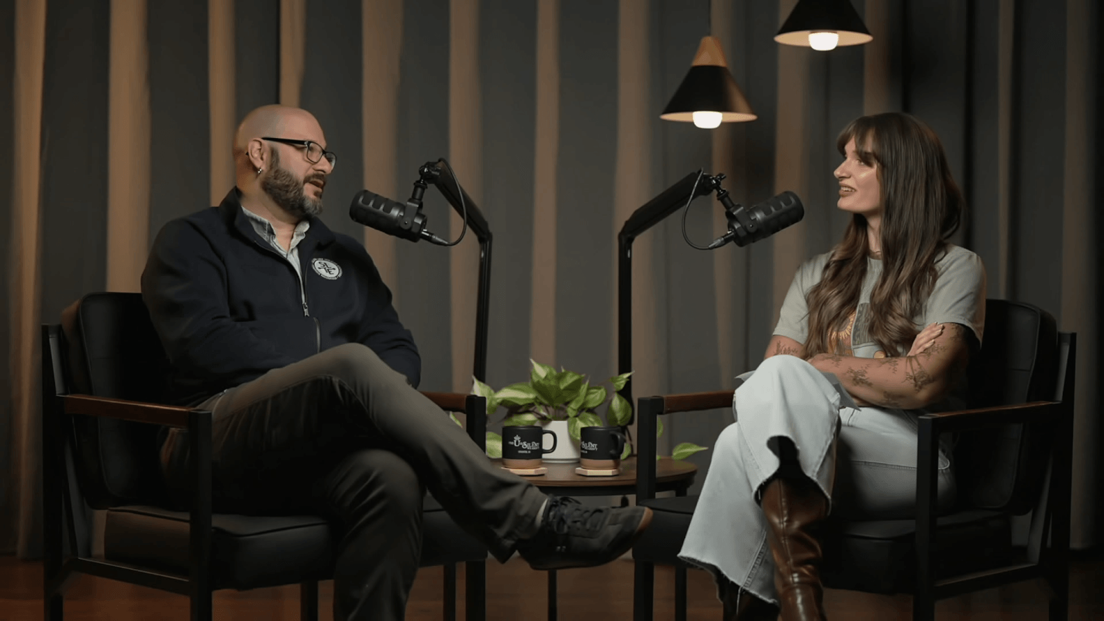 Jeremy and samantha both sit behind podcast microphones in conversation